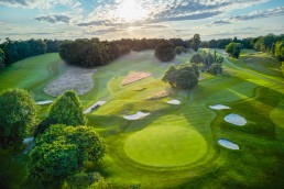 Aerial view of hole 2 at Addington Palace Golf Club, with the green in the foreground, surrounded by bunkers