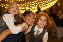 Three children smiling at the camera during a wedding reception at Addington Palace Golf Club